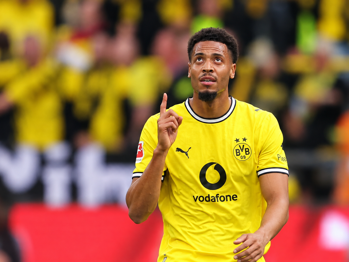 Felix Nmecha von Borussia Dortmund im gelben Trikot blickt nach oben und hebt einen Finger.
